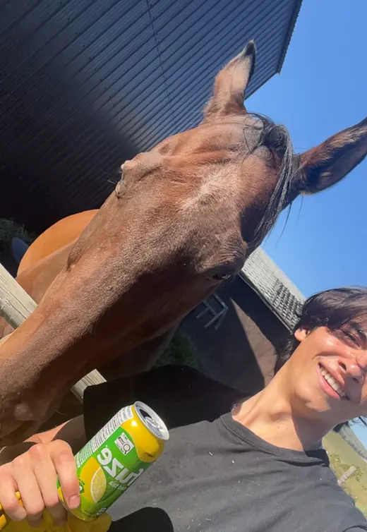 Ayden, smiling, taking a selfie with a horse leaning over a fence in Alberta